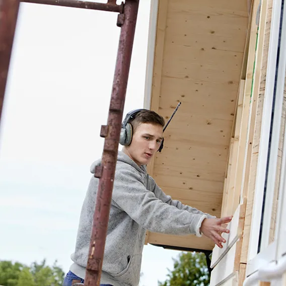 Hantverkare på byggnadsställning lägger plankor på hus