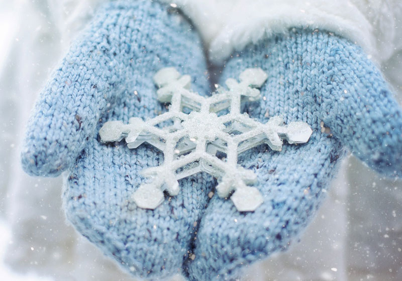 närbild på händer i vantar som håller snöstjärna