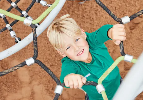 Barn i klättringsnät på lekplats